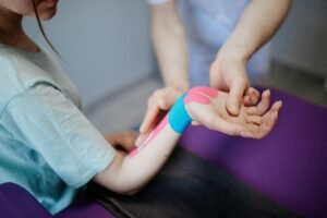 physiotherapist-restore-ankle Close-up of a therapist applying kinesio tape for pain relief during a therapy session.